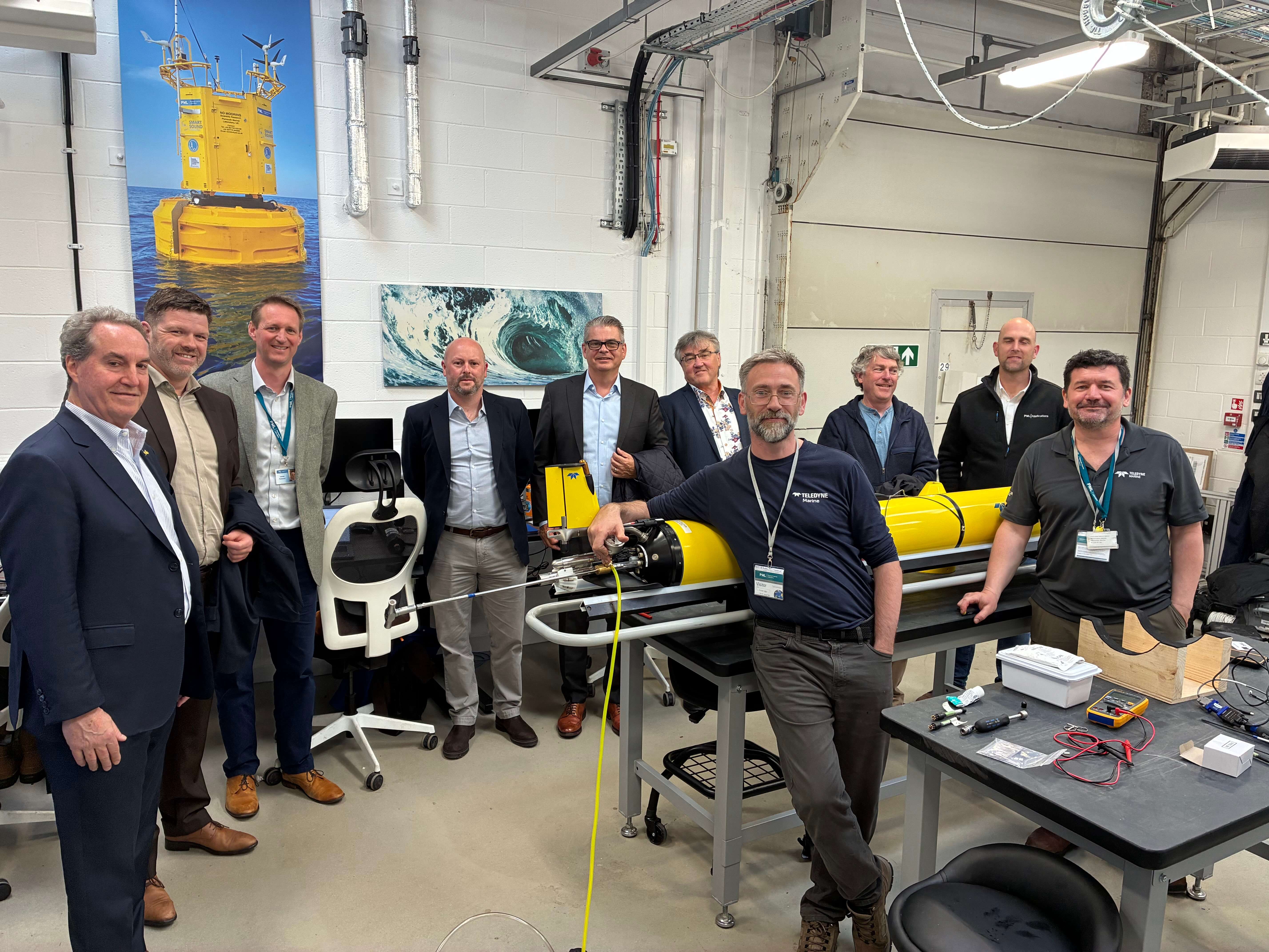 A group of people posing for a photo inside a room with marine equipment.